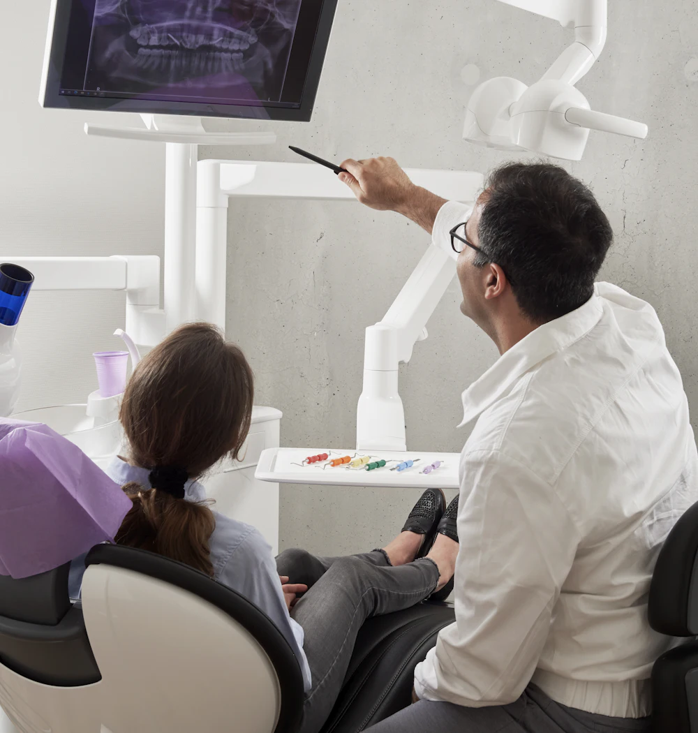 A dentist talking with a relaxed patient in the chair